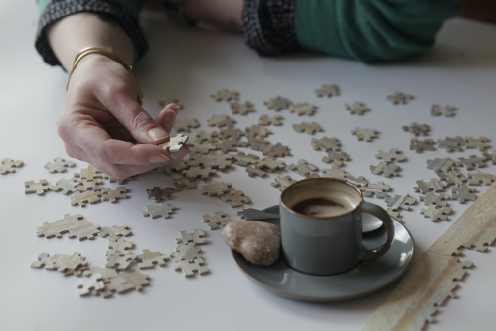 Image of a person working on a puzzle with a coffee