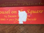 Image of the puzzle 1000, SunsOut, Carousel on the Square, by Susan Brabeau, Complete, Detail of the box